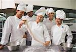 Chefs watching pastry chef stretch piece of dough