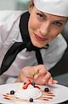 Smiling chef putting mint leaf on meringue dish