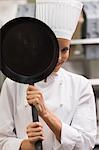 Chef smiling from behind frying pan