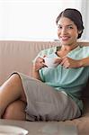 Happy businesswoman having coffee sitting on sofa