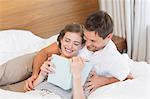 Happy couple on bed reading a book