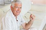 Happy senior man sitting on the couch holding glasses