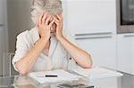 Worried senior woman paying her bills