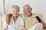 Happy senior couple watching tv on the couch