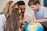 Close-up of a family of four looking at globe