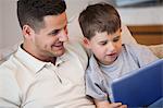 Father with son using digital tablet in living room