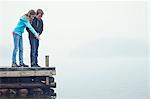 Boy and girl on jetty looking at water, Okno, Smiland, Sweden
