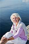 Smiling senior woman sitting on jetty, Bohuslan, Sweden