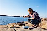 Man having grill on cliff, Bohuslan, Sweden