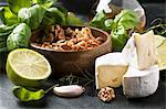 Cheese Camembert, walnuts, fresh basil and lime over dark bakground