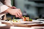 Chef plating up pork dish during service at working restaurant