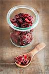 Dried cranberries in a jar and on a wooden spoon