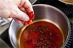 a hand puts paprika powder into a pot for paprika sauce