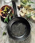 An empty pan, sage, black and green olives, olive oil, an olive sprig, olive ciabatta and lavender