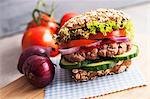 A wholemeal roll with minced beef, kethcup, gherkins, red onions, tomatoes and lollo rosso lettuce