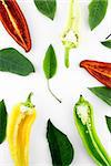 red, yellow and green hot chili pepper slices with leaves on a white background