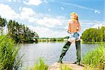 young woman fishing at pond in summer