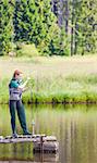 young woman fishing on pier at pond