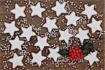 Christmas star gingerbread biscuits with holly and silver balls over old oak wood background
