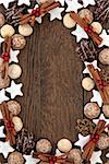 Christmas biscuit food background with cinnamon sticks and red bauble decorations over old oak wood.