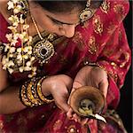 Beautiful Indian female hands holding diya oil lamp, celebrating diwali festive of lights, traditional sari prayer isolated on black background with copy space on side.