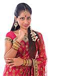 Portrait of beautiful young Indian girl in traditional sari dress thinking, looking at camera, standing isolated on white background.