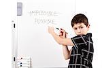 young boy student in a classroom writing possible on a empty whiteboard