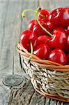 cherry in straw basket isolated on old wooden background