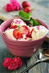 Ice cream with strawberries on old wooden table.