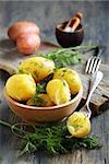 Potatoes with butter and dill in a bowl on a wooden table.