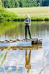 young woman fishing on pier at pond