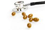 pills with unfocused stethoscope on background on the white table