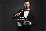 Portrait of a beautiful latin man with tuxedo and holding a clapboard