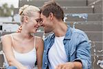 Hip young couple in denim sitting on steps on a sunny day in the city