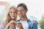 Cute young couple looking at smartphone on a sunny day in the city