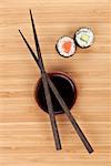 Maki sushi, chopsticks and soy sauce on bamboo wooden table background