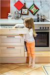 Little girl getting tableware from table case before dinner