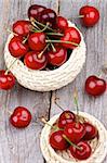 Sweet Ripe Cherries in Wicker Bowls isolated on Rustic Wooden background. Top View