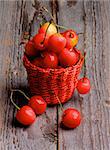 Sweet Maraschino Cherries in Red Wicker Basket isolated on Rustic Wooden background