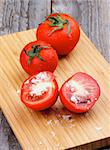 Ripe Tomatoes Full Body and Halves with Salt Flakes on Wooden Cutting Board