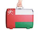 Used plastic suitcase with stains and scratches, printed with flag, Oman