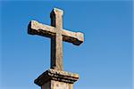 Stone cross in a column with clear blue sky as background.