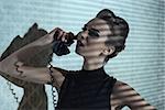 sensual elegant girl with creative hair-style and dark dress speaking on vintage phone in indoor half-light atmosphere with interrogative expression