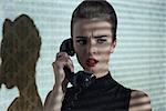 indoor fashion shoot of elegant woman with stylish make-up and dark dress talking on vintage phone with dramatic expression