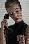 fashion girl with elegant hair-style and stylish make-up listening gossip on the retro phone in indoor half-light atmosphere
