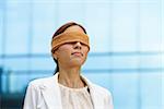 Concept of future and forecasting. Portrait of latina blindfolded businesswoman near office building