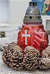 Red candle and pine cones on a marble grave in Brasov, Romania
