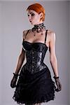 Pretty redhead young woman in silver corset and black skirt, studio shot