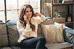 Happy young woman talking cell phone in loft apartment