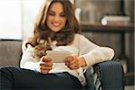 Closeup on happy young woman writing sms in loft apartment